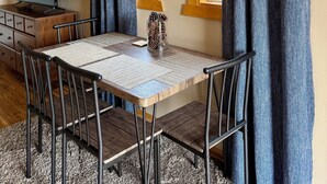 Un comedor con una mesa, sillas, un jarrón con piñas y un televisor sobre un mueble de madera.