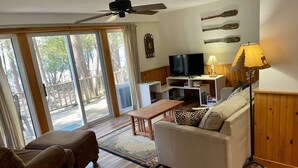 Uma sala de estar com um sofá, uma mesa de centro, uma televisão e um abajur.