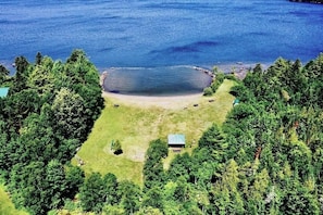 A lakeside property with a small cabin, surrounded by dense forest and a clear view of the lake.