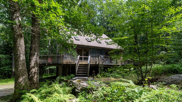 Eine Holzhütte mit einer Veranda und einer Treppe zu einem Balkon im zweiten Stock.