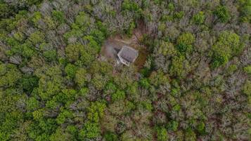 An aerial view of a forested area with a small building surrounded by dense trees.