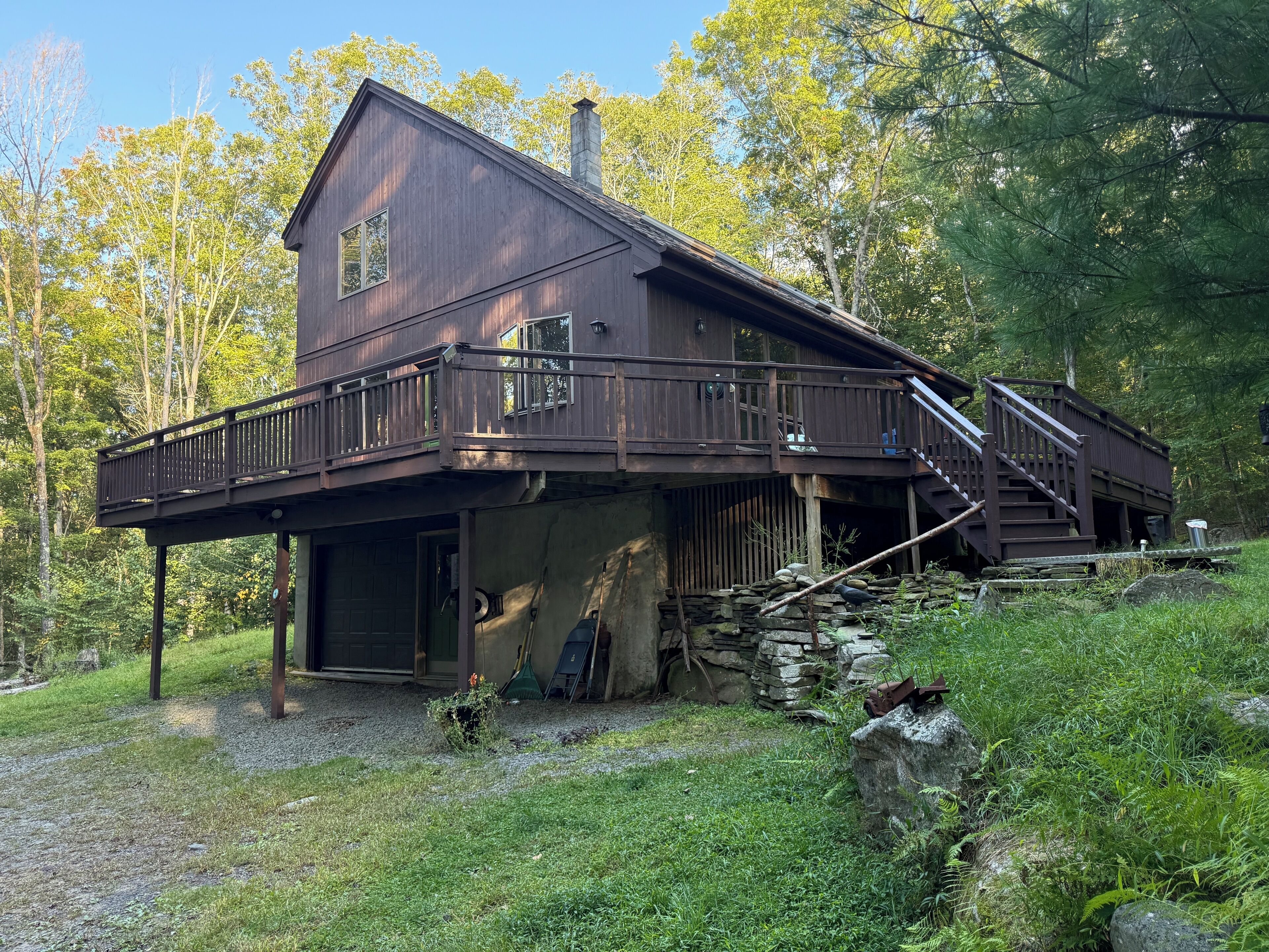 A two-story wooden cabin with a balcony and a staircase leading to an upper deck.
