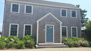 A two-story house with a gray exterior, white trim, and a blue door. The address "38" and "Monkey Barrel" are visible above the door.