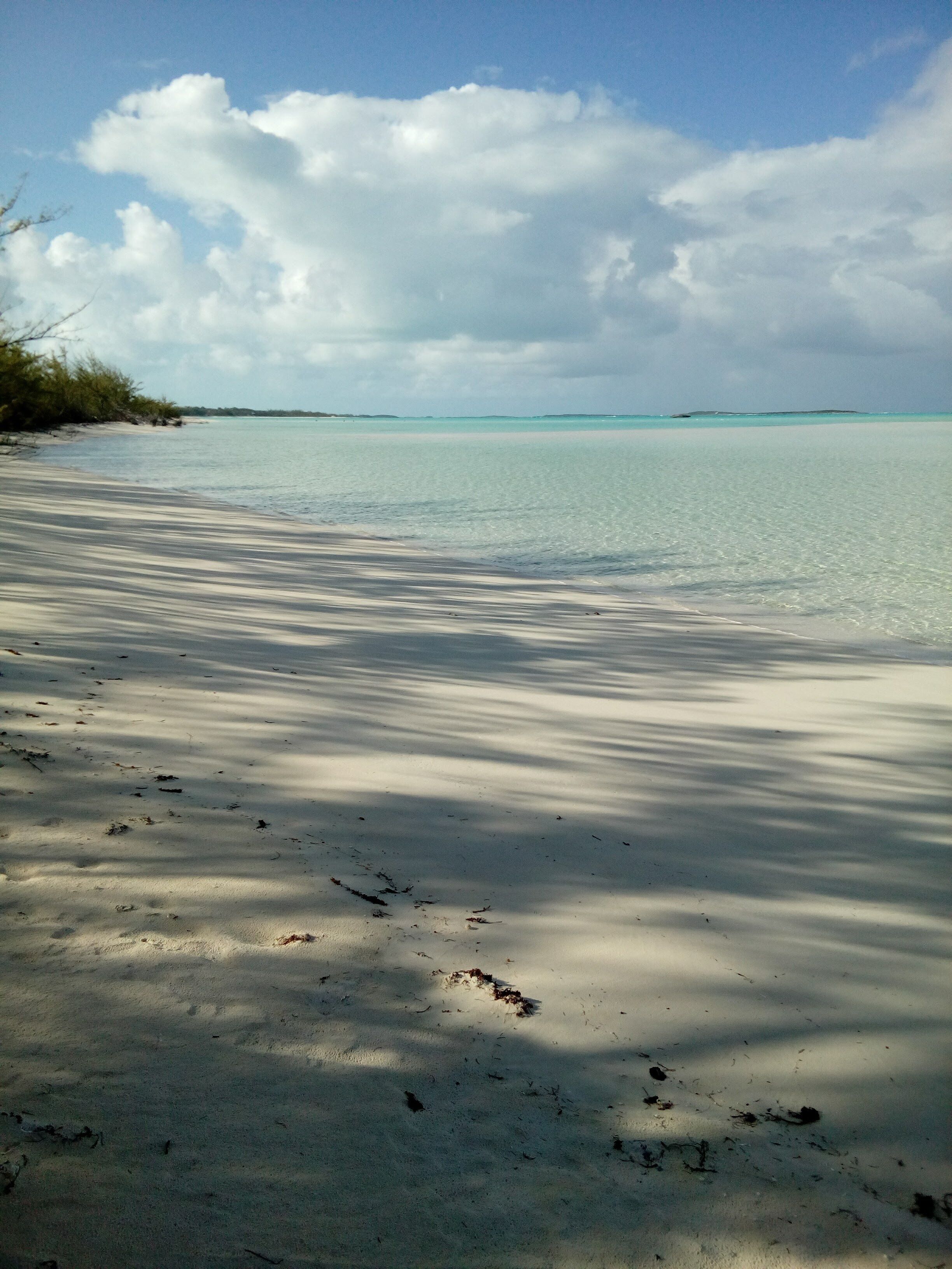 A beach with clear turquoise water and a sandy shore.