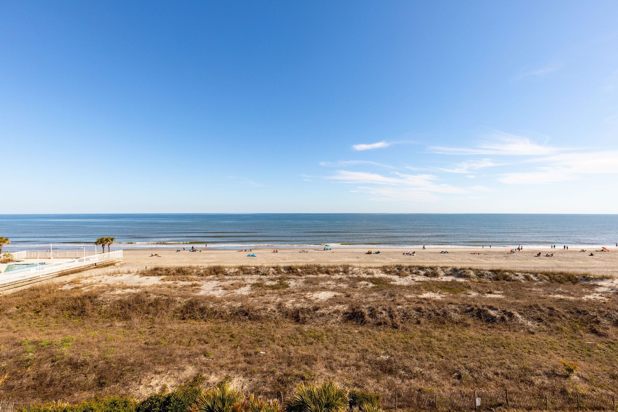A beach with a fenced area, a pool, and a view of the ocean.
