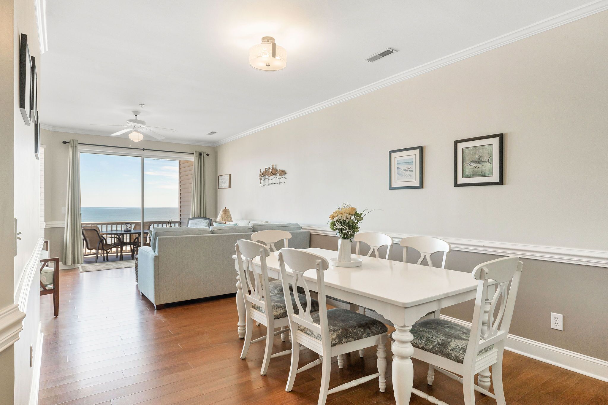 A dining area with a white table and chairs, a ceiling fan, and a view to the outside.