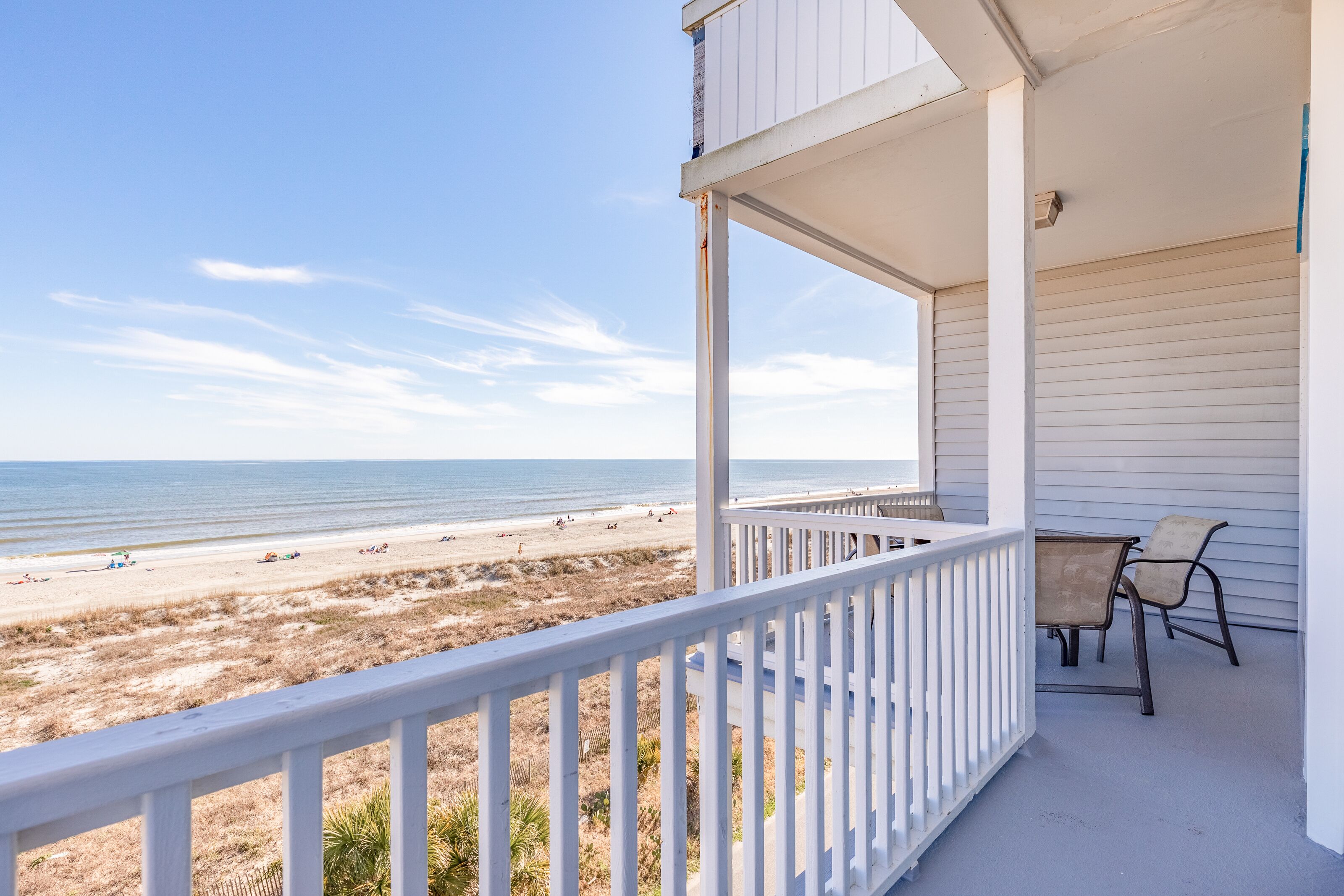 A balcony with a view of the beach and ocean.