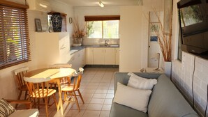 Une cuisine moderne avec des meubles blancs, une table à manger avec des chaises et un canapé gris.