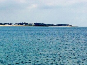A coastal view with a beach and a row of buildings along the shore.