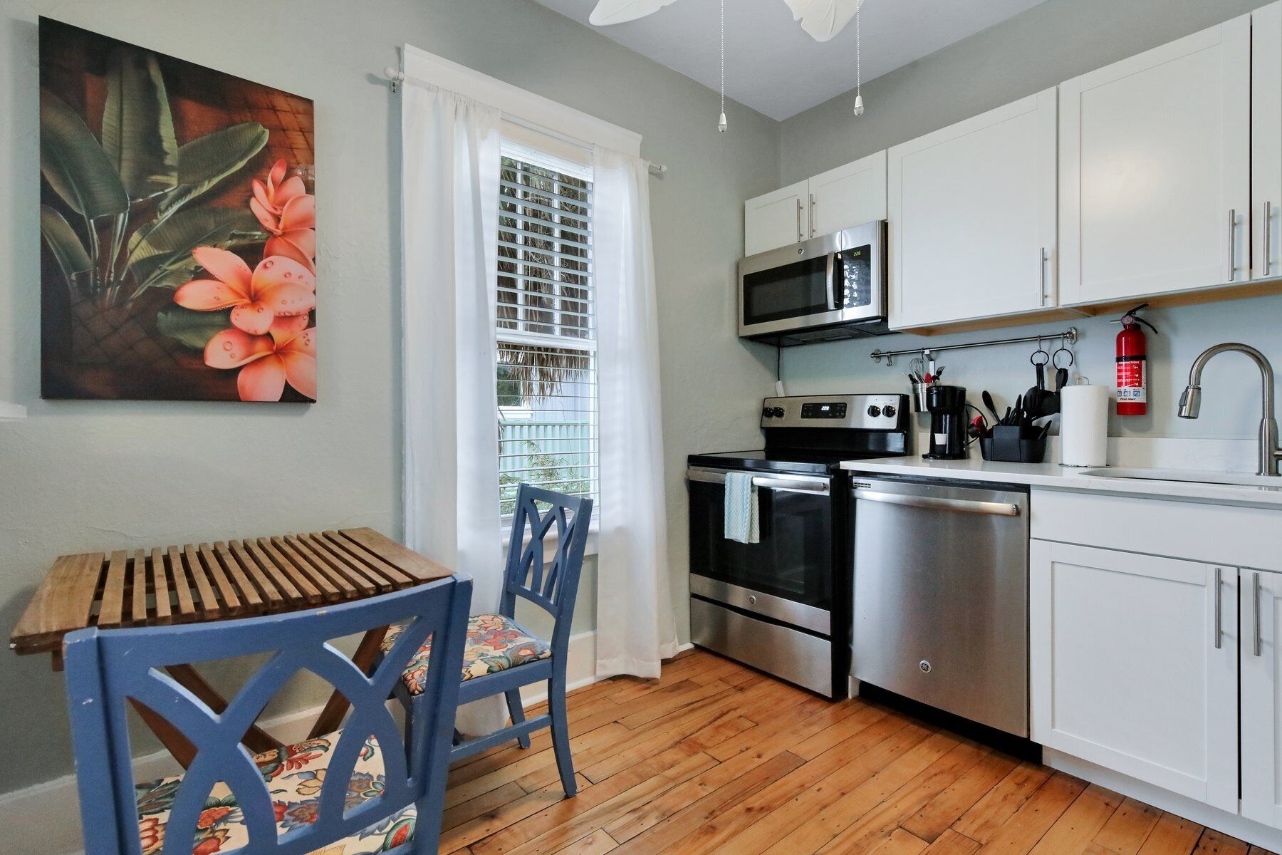 A modern kitchen with white cabinets, stainless steel appliances, and a wooden dining table.