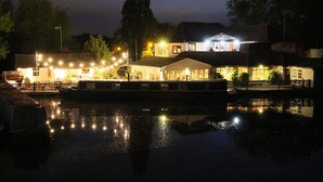 Un hotel sul lungomare con diversi edifici, un molo e una superficie d'acqua calma che riflette le luci.