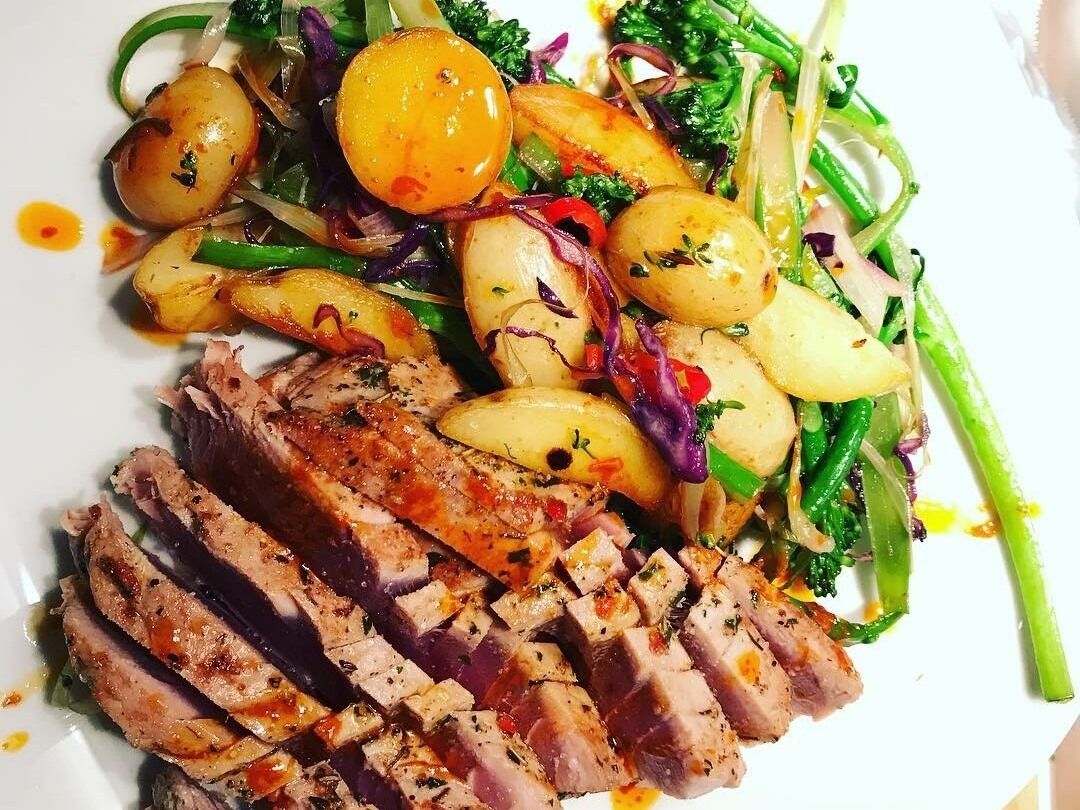 Un plato de comida con carne en rodajas, patatas y verduras.