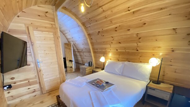 Una camera da letto accogliente in una baita di legno, con un letto, lampade sui comodini e un piccolo tavolo.