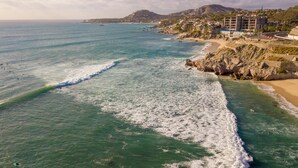 Une zone côtière avec une plage, une côte rocheuse et des bâtiments en arrière-plan.
