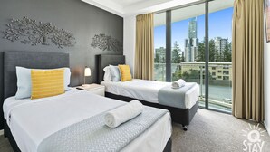 A hotel room with two beds, a nightstand, a lamp, and a large window with a city view.
