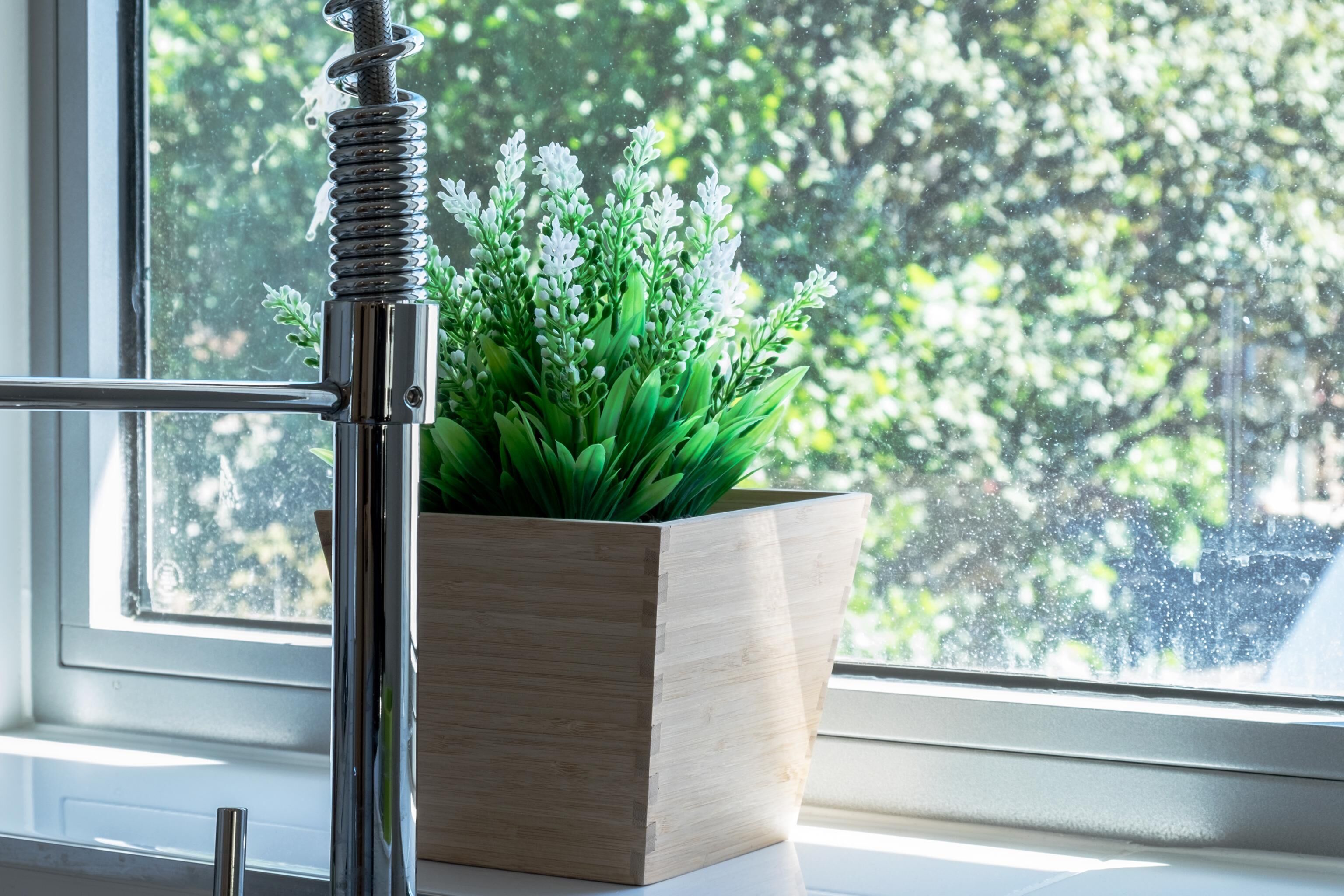 Una caja de madera para plantas con follaje verde sobre un alféizar.