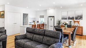 A modern kitchen with white cabinets, a dining area with a wooden table and chairs, and a grey sofa in the living area. - Olinda Two Bedroom Apartment B2 - This beautiful and comfortably furnished apartment is centrally located in the village of Olinda. (Olinda)