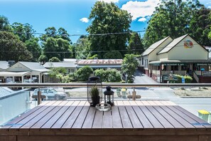 Una terraza de madera con vistas a un pueblo, incluyendo un restaurante y una cafetería.