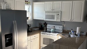 Una cocina moderna con armarios blancos, un refrigerador de acero inoxidable, un microondas y una estufa.