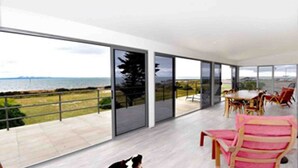 A spacious room with large sliding glass doors leading to a balcony with a view of the sea.