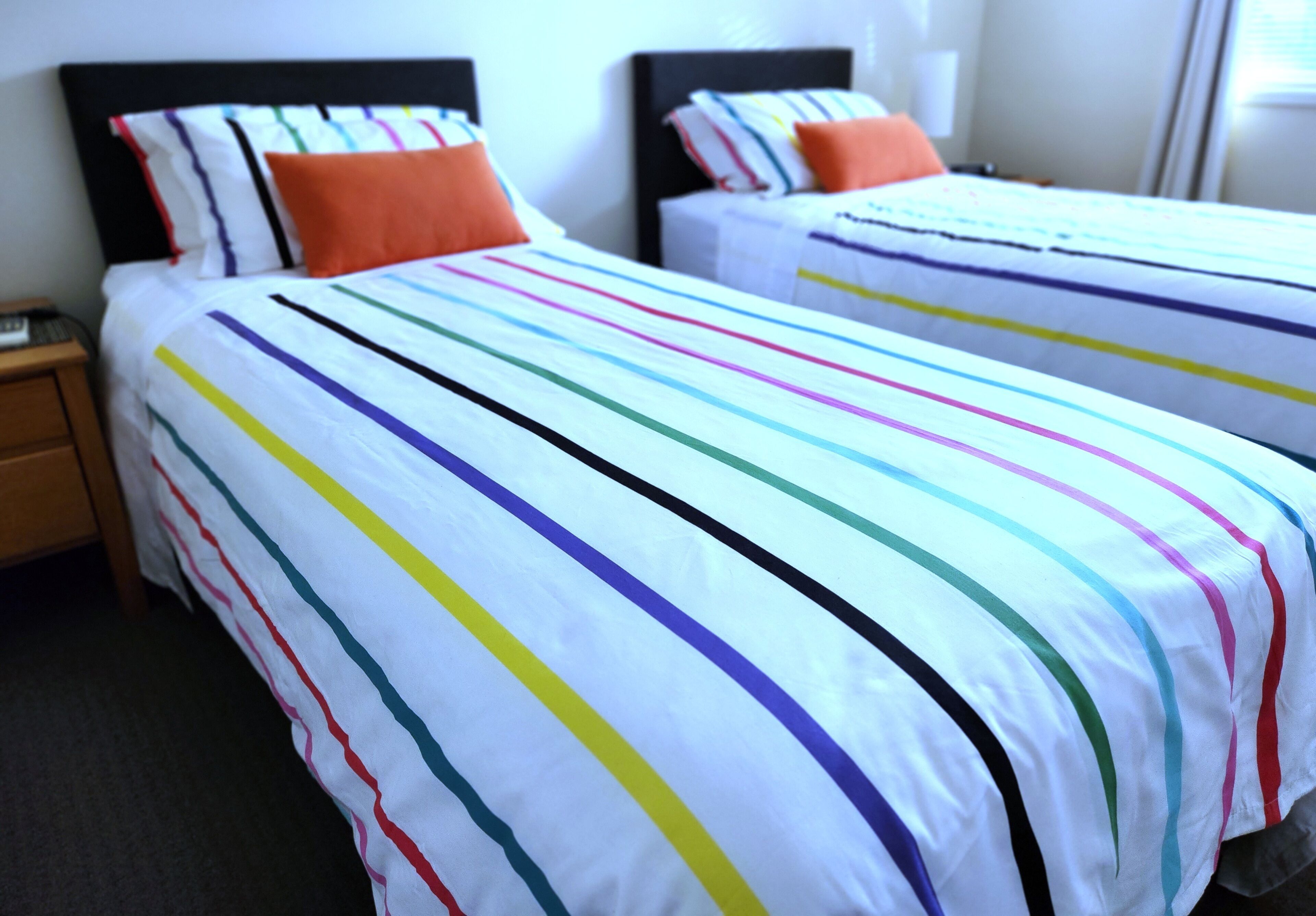 A hotel room with two beds, each with striped bedding and matching pillows.
