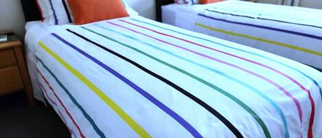 A hotel room with two beds, each with striped bedding and matching pillows.