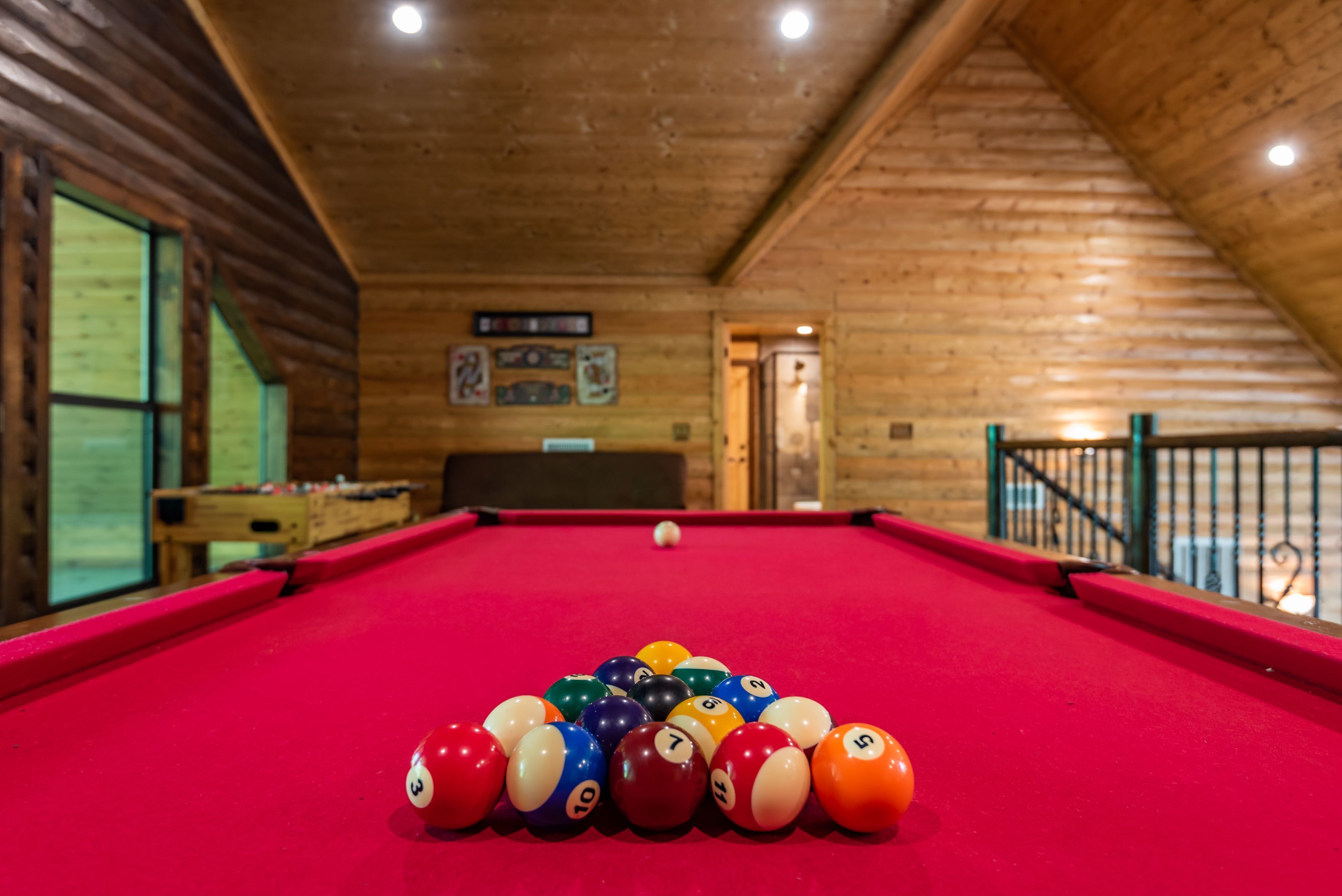 Una mesa de billar con bolas dispuestas en triángulo, paredes y techo de madera.