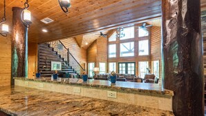 A spacious kitchen with granite countertops, a central island, and a staircase leading to a loft area.