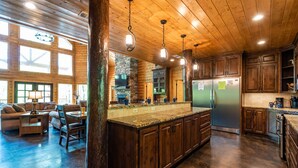 A spacious kitchen with wooden cabinets, a large island, and a stone fireplace.