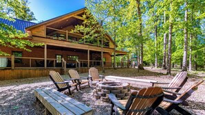 A lodge with a wooden exterior, outdoor seating area with Adirondack chairs, and a fire pit.