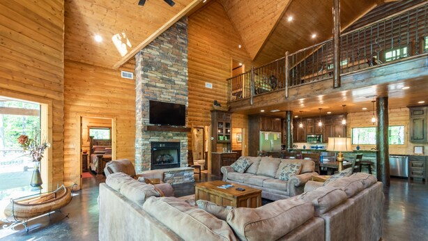 A spacious living area with a stone fireplace, leather sofas, and a wooden boat decoration.