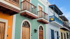 A street with colorful buildings, a cobblestone road, and a person sitting on a bench. - Rio Mar Beach Resort - Time Magazine TOP 100 World's Greatest Places  2018 (Rio Grande)