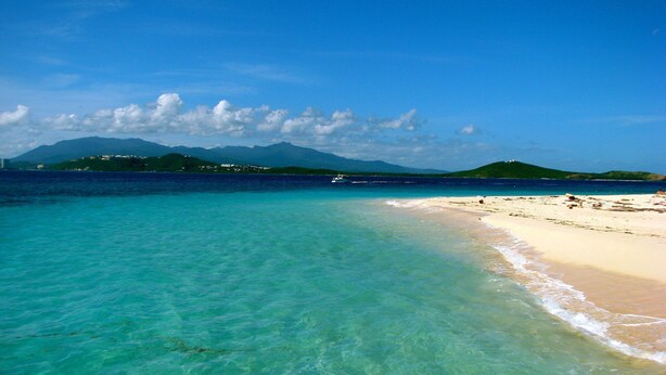 A beach with clear turquoise water, a sandy shore, and distant mountains. - Rio Mar Beach Resort - Time Magazine TOP 100 World's Greatest Places  2018 (Rio Grande)
