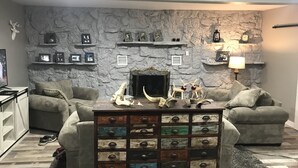 A living room with a stone wall, two sofas, a coffee table with decorative items, and a fireplace.