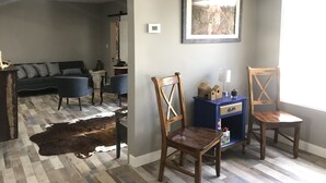 A living room with a sofa, chairs, a cowhide rug, a blue cabinet, and a framed picture on the wall.