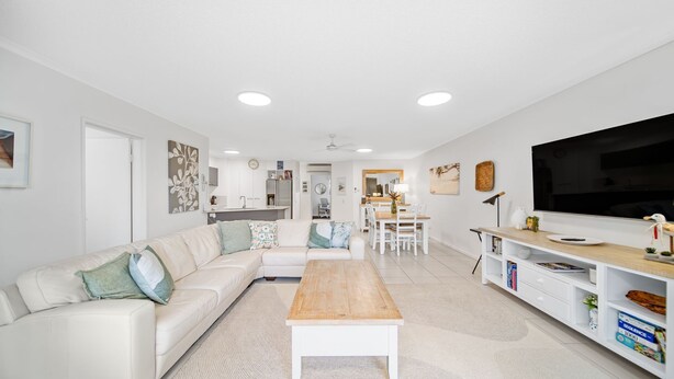 A modern living room with a white sofa, a wooden coffee table, and a TV on a white stand. - Unit 2 'Point Break' (Point Arkwright)