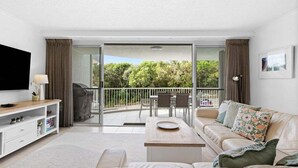 A modern living room with a sofa, TV, and a balcony with a table and chairs. - Unit 2 'Point Break' (Point Arkwright)