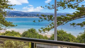 A coastal view with a beach, ocean, and distant cityscape.
