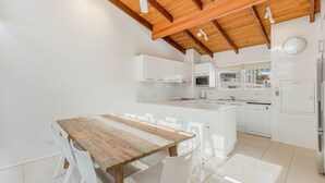 A modern kitchen with white cabinetry, a wooden dining table, and a built-in island.