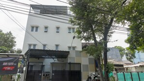 A multi-story building with a gated entrance, a motorcycle parked outside, and a banner advertising a tech product. - RedDoorz near Central Park Mall (Jakarta)