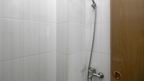 A shower area with white tiled walls and a wooden door. - RedDoorz near Central Park Mall (Jakarta)