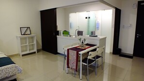 A compact room with a bed, a small table with chairs, a kitchenette, and a mirror above the counter. - 1 Bedroom Apartment @ Trefoil Setia Alam (Shah Alam)