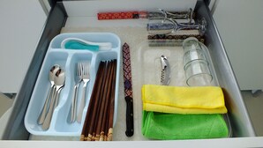 A drawer with utensils, a knife, a bottle opener, a glass, and a towel. - 1 Bedroom Apartment @ Trefoil Setia Alam (Shah Alam)