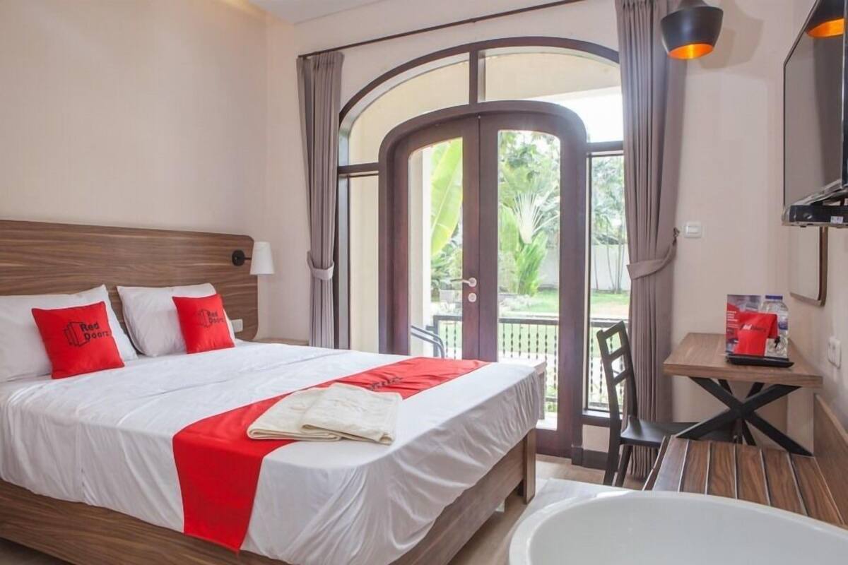 Habitación de hotel con cama, mesa, silla, bañera y vista al exterior.