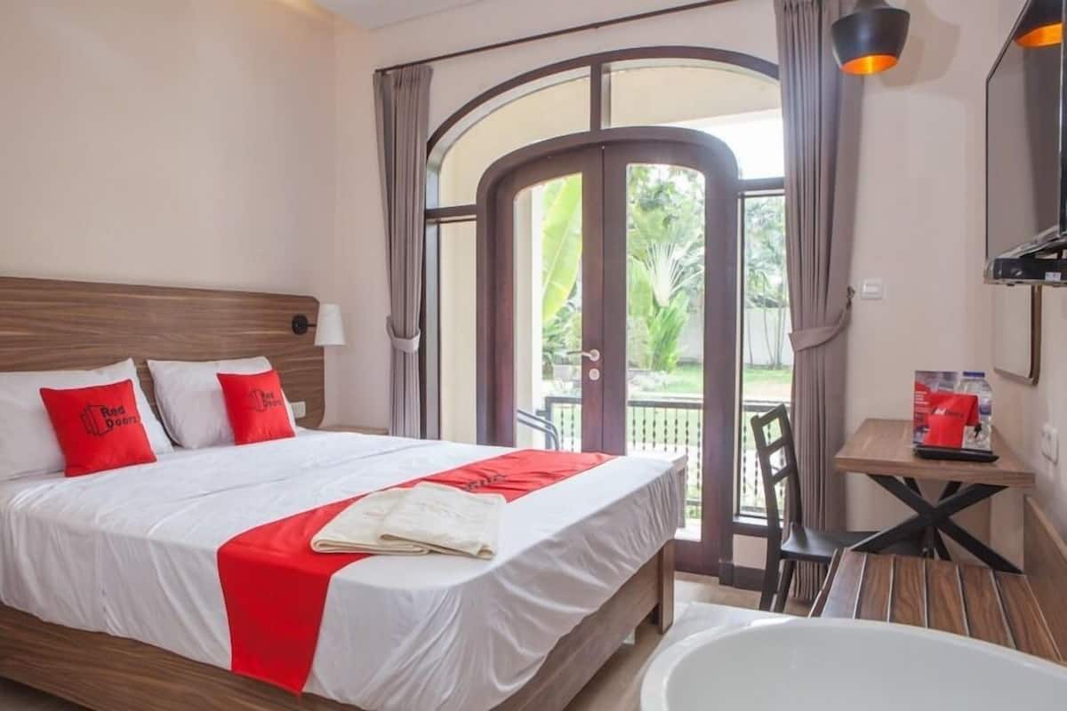 Habitación de hotel con cama, mesa, silla, bañera y vista al exterior.