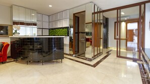 A modern kitchen with a black countertop, white cabinets, and a green plant. - RedDoorz Plus @ CBD Bintaro (South Tangerang)