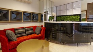 A modern kitchen with a black countertop, a red sofa with striped cushions, and a green plant on the counter. - RedDoorz Plus @ CBD Bintaro (South Tangerang)