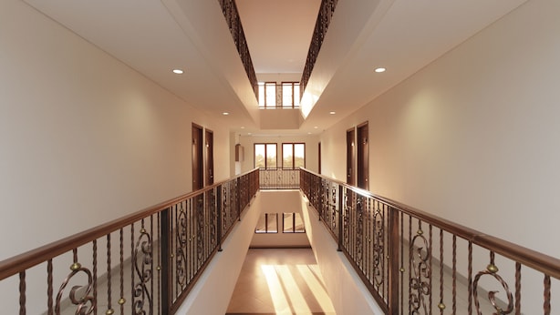 A spacious, well-lit hallway with a wooden staircase and ornate metal railings. - RedDoorz Plus @ CBD Bintaro (South Tangerang)