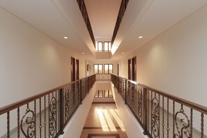 Un hall spacieux et bien éclairé, doté d’un escalier en bois et de rampes en métal décorées.