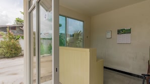 Zona de recepció amb una porta de vidre, una taula de recepció de fusta i un calendari penjat a la paret.